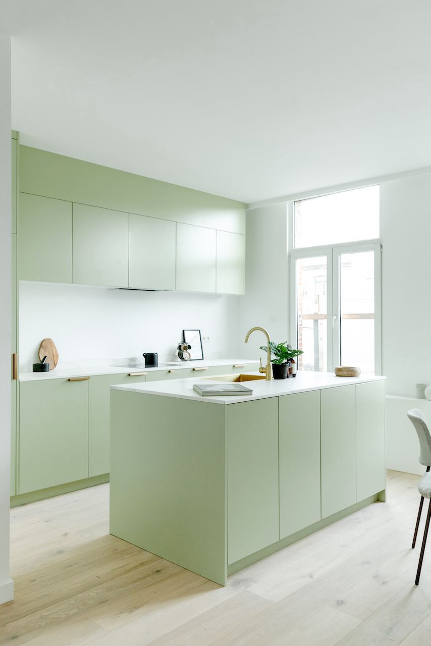 Saliegroene keuken met eiland in een lichte ruimte